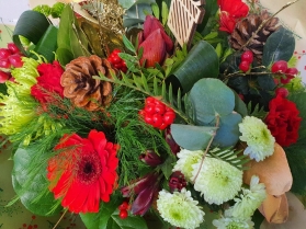 Red and green flower handtied bouquet in a gift bag