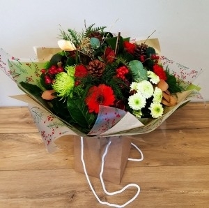 Red and green flower handtied bouquet in a gift bag